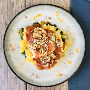 Polenta tibia a la napolitana con base de espinaca y costra de nueces